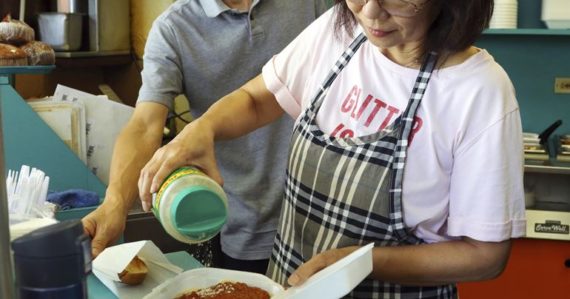 Belinda Lauová, manažérka honolulskej reštaurácie, sype syr na špagety, ktorý sú v plastovom obale