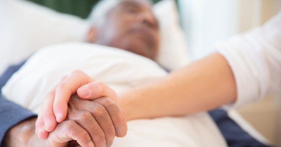 Umierajúci senior drží za ruku svoju blízku osobu