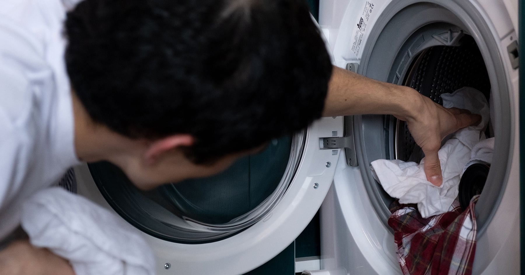 Muž vyťahuje bielizeň z práčky