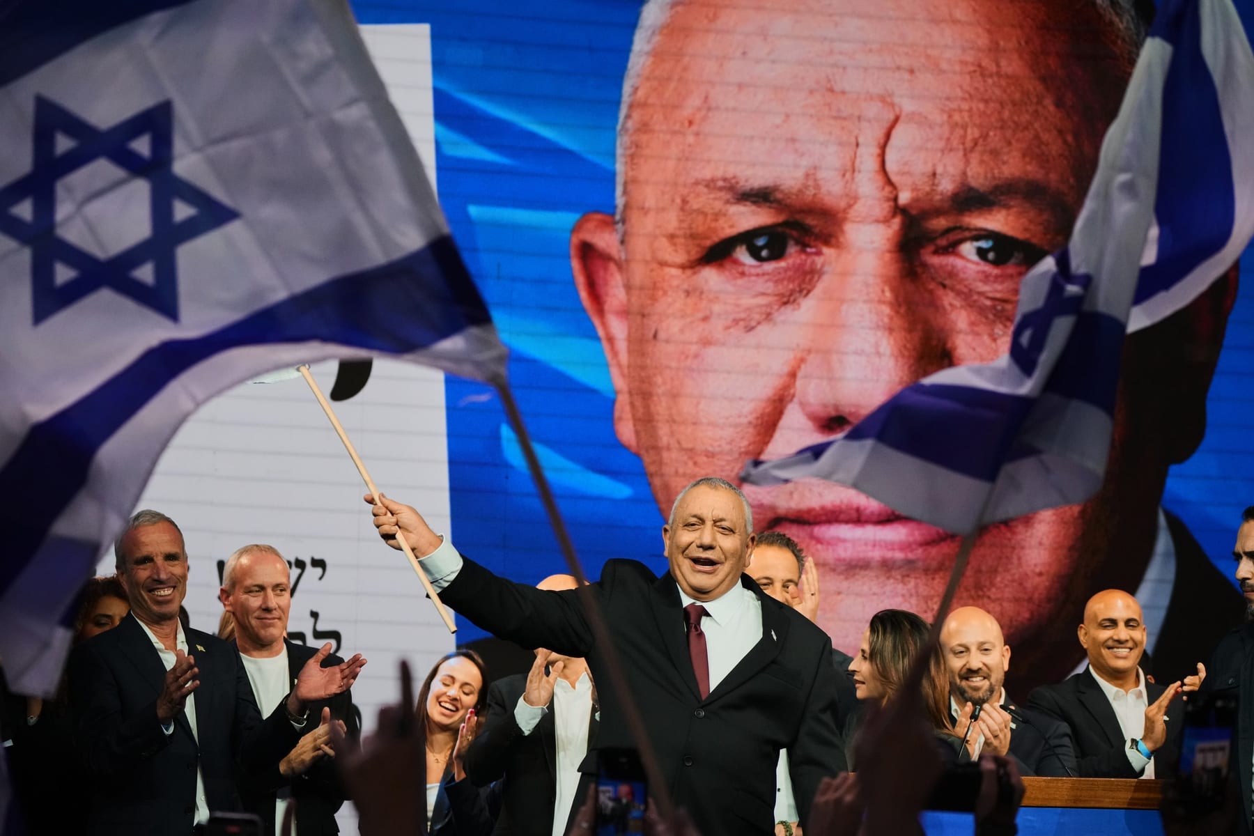 Gadi Eisenkot, líder strany Yashar, máva izraelskou vlajkou na pódiu po zverejnení odhadov volieb v Tel Avive.