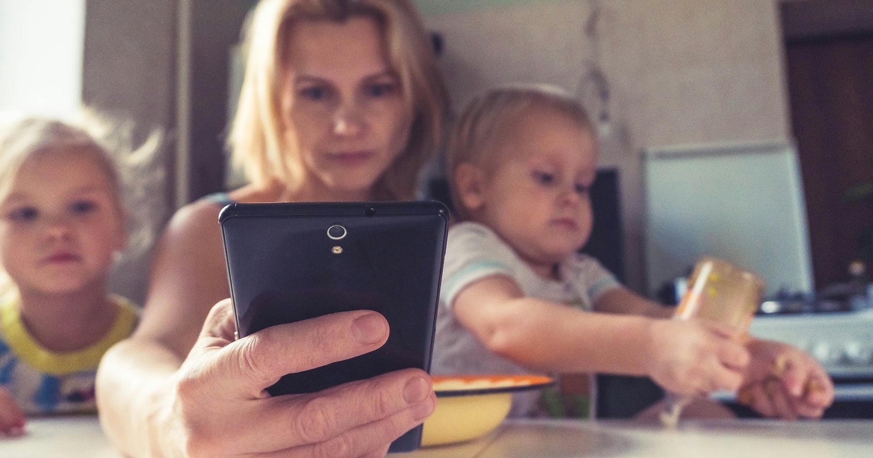 Matka s mobilom v ruke a s deťmi
